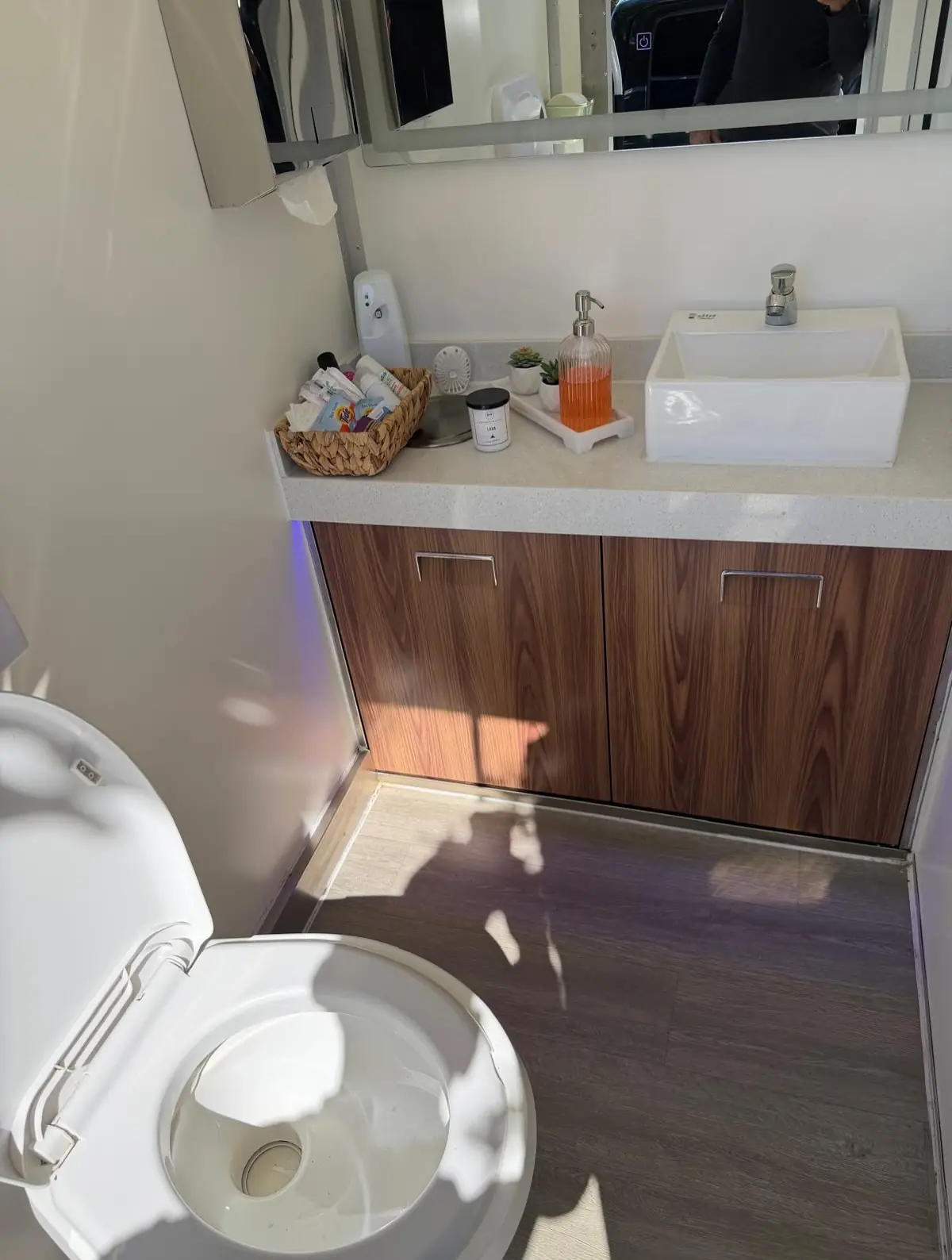 Restroom trailer interior with wood vanity, sink and flushing toilet